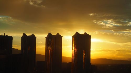 Silhouette of skyscrapers against sunset sky