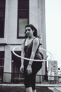 Young woman plastic hoop while standing against building