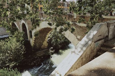 Arch bridge over river against trees
