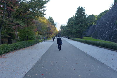 Rear view of man walking on footpath