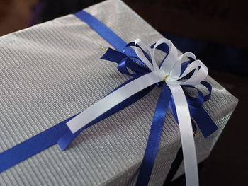 Close-up of gift with white and blue ribbon