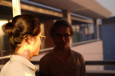 Young man wearing eyeglasses in front of glass window with reflection