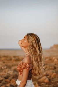 Side view of woman standing on land against clear sky