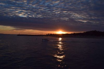 Scenic view of sea against cloudy sky during sunset