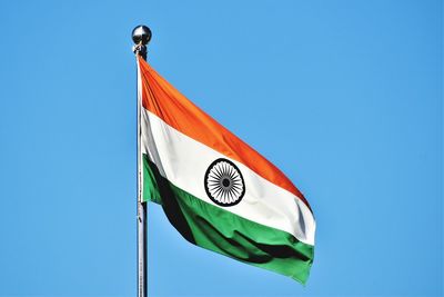 Low angle view of flag against clear blue sky