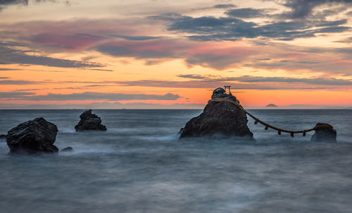 Rock formations in sea against sky during sunset