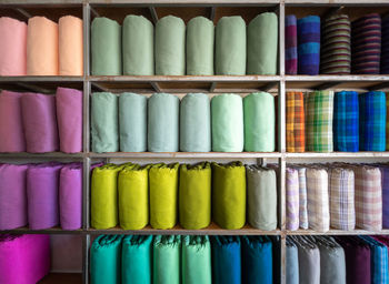 The handmade woven silk rolls in traditional thai style are on shelves inside a local clothing store