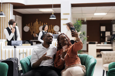 Female friends using phone while sitting in meeting