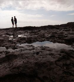 People standing on beach against sky