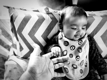 Cropped hand holding baby girl hand at home