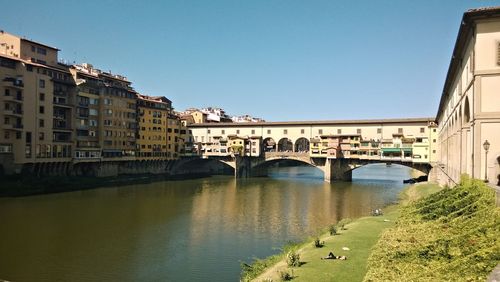 Bridge over river in city against clear sky