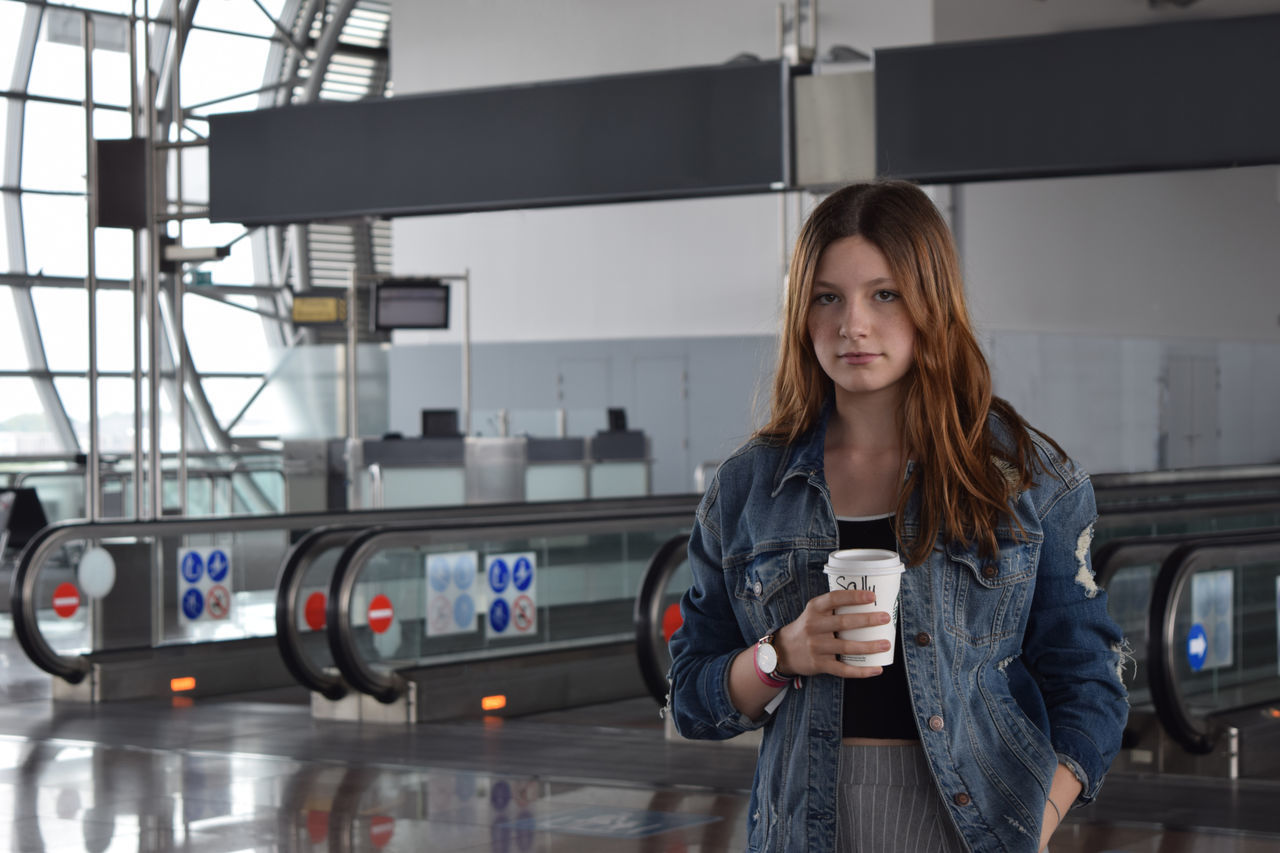 PORTRAIT OF BEAUTIFUL YOUNG WOMAN STANDING AT BUS