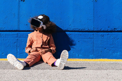 Full length of man sitting against blue wall