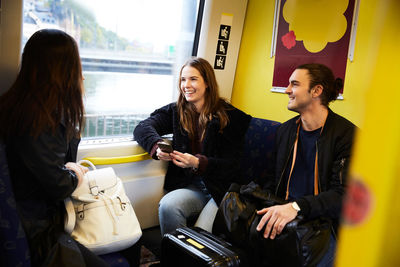 Smiling young friends traveling in yellow train