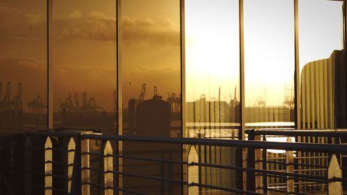 Man sitting by railing against buildings during sunset