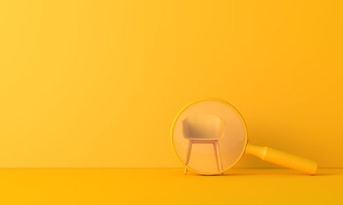 Chair seen through magnifying glass against yellow background