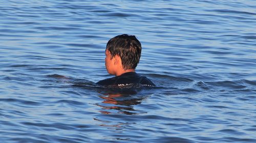 Rear view of boy swimming in sea