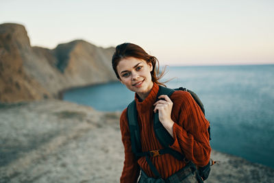 Portrait of young woman standing in sea against sky