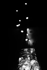 Low angle view of illuminated lights against black background