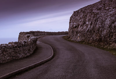 Road amidst rocks against sky
