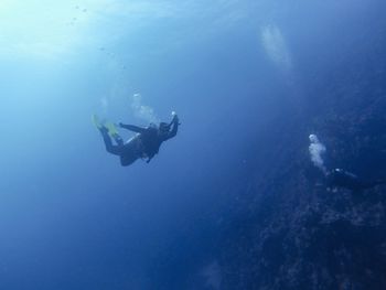 Scuba divers swimming through blue ocean