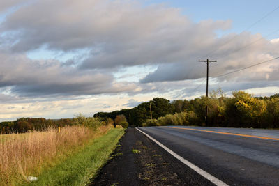 Road amidst field against sky