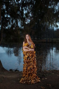Portrait of young woman standing by lake