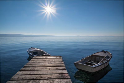 Boat moored by pier on lake against sky