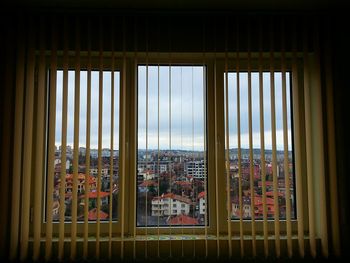 Cityscape against sky seen through window blinds