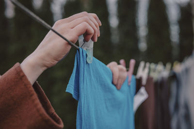 Woman putting clothespin on clothes hanging on string at back yard