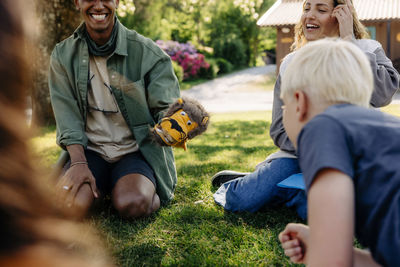 Camp counselors playing with kids while sitting on grass at summer camp