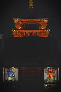 Low angle view of illuminated statue against building at night