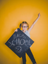 Portrait of woman standing against yellow wall