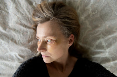 Close-up portrait of young woman lying on bed