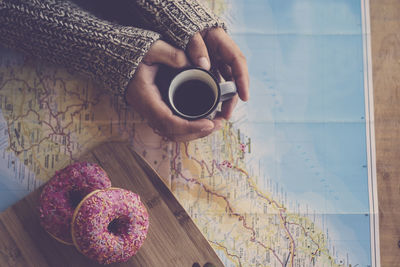 High angle view of woman holding coffee cup on table