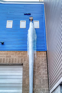 Low angle view of glass building against blue wall