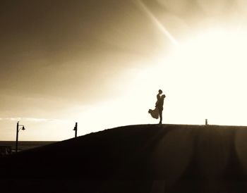 Silhouette woman standing on landscape at sunset