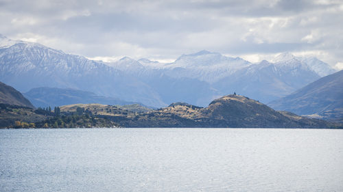 Landscape panorama with lake and hills and big snowy mountains in backdrop, new zealand