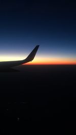 Airplane wing against sky during sunset