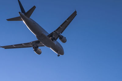 Low angle view of airplane against clear blue sky