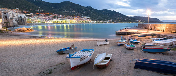 Boats moored on sea by city against sky