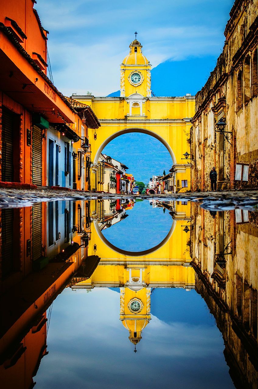 architecture, built structure, sky, reflection, water, place of worship, religion, building exterior, cloud - sky, spirituality, waterfront, arch, day, outdoors, yellow, puddle, symmetry, no people