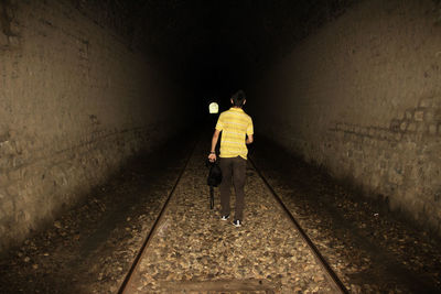 Rear view of man walking in tunnel