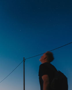 Low angle view of man standing against clear sky at night