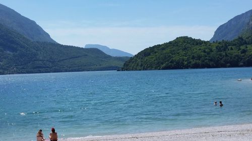 People on beach by mountain against sky