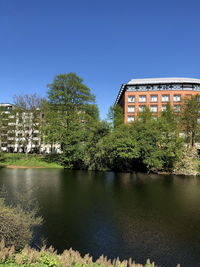 Building by lake against clear blue sky