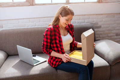 Young woman using phone while sitting on sofa at home