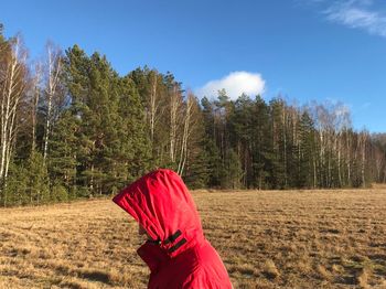 Woman with red umbrella on field against sky