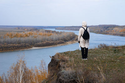 Rear view of woman walking on field against sky