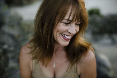 Close-up of happy woman looking away while sitting at park during sunset